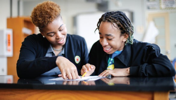 A city year corps member working closely with middle-school student who is reading