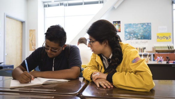 AmeriCorps member in yellow jacket watched student complete assignment,