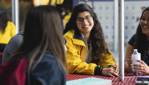 A City Year AmeriCorps member sits in an outdoor table with a small group of students