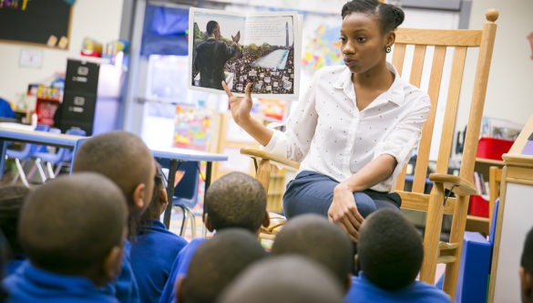 A City Year alumni reading a book to young students sitting on the floor