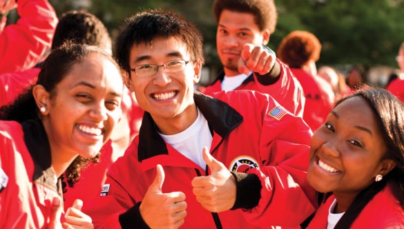 A group of AmeriCorps members smile with their thumbs up.
