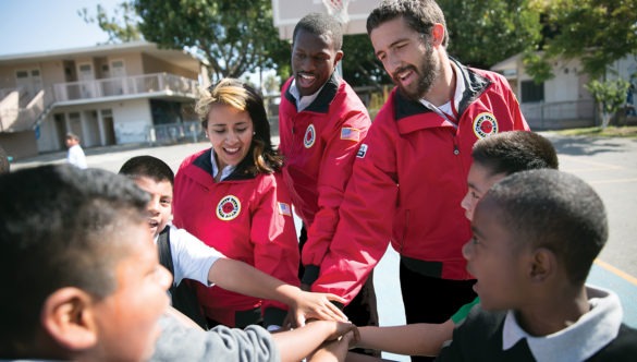 americorps members place their hands in a spirit break with students