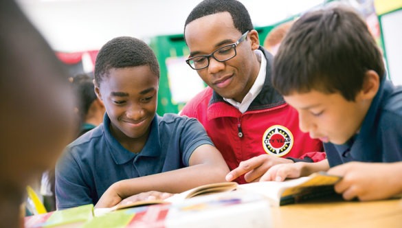 a middle school student smiles while reading with an AmeriCorps member