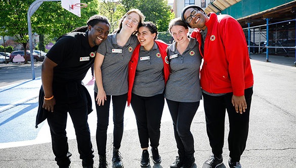 Group of five City Year AmeriCorps members arm in arm smiling at the camera