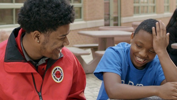 City Year AmeriCorp Member and student sitting at a table talking to each other