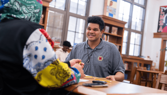 City year Columbus AmeriCorps member smiles at a student wearing a hoodie
